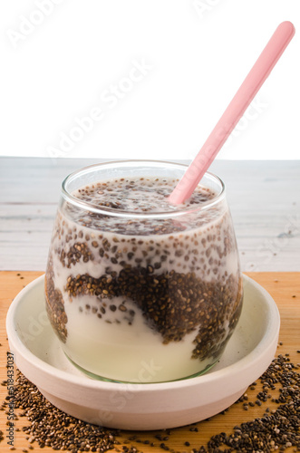 glass of milk with chia seeds and spoon on white background