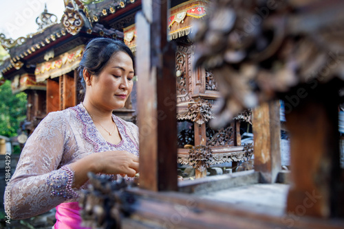 Balinese woman putting offerings on a family temple photo