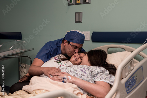 Parents kissing their daughter photo