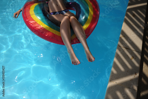 A teenage girl plays in a swimming pool with a rainbow pool float photo