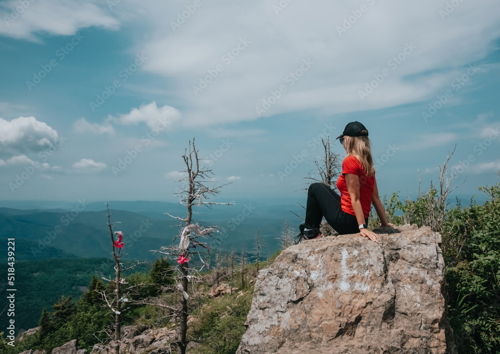 Fototapeta premium A girl on top of Falaza mountain looks at a beautiful mountain valley. Travel and tourism. Hiking