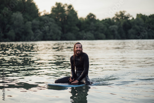 Surfer man driving e-foil during day on city river photo