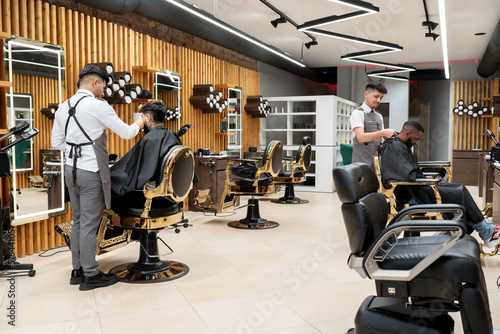 Barbers Working With Their Clients At Barbershop photo