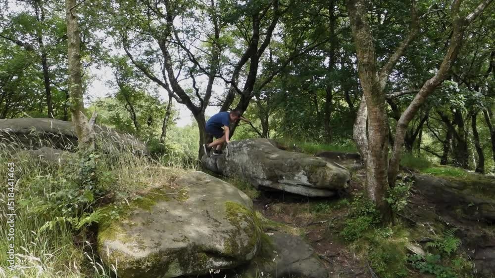 Young boy climbing and jumping on the rocks at Brimham Rocks, once known as Brimham Crags in North Yorkshire, surrounded by woodland in the UK. Young boy climbing and jumping on the rocks at Brimham Rocks, once known as Brimham Crags in North Yorkshire, surrounded by woodland in the UK.