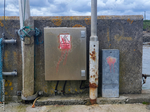 An electricity supply box on a harbour wall with danger signs photo
