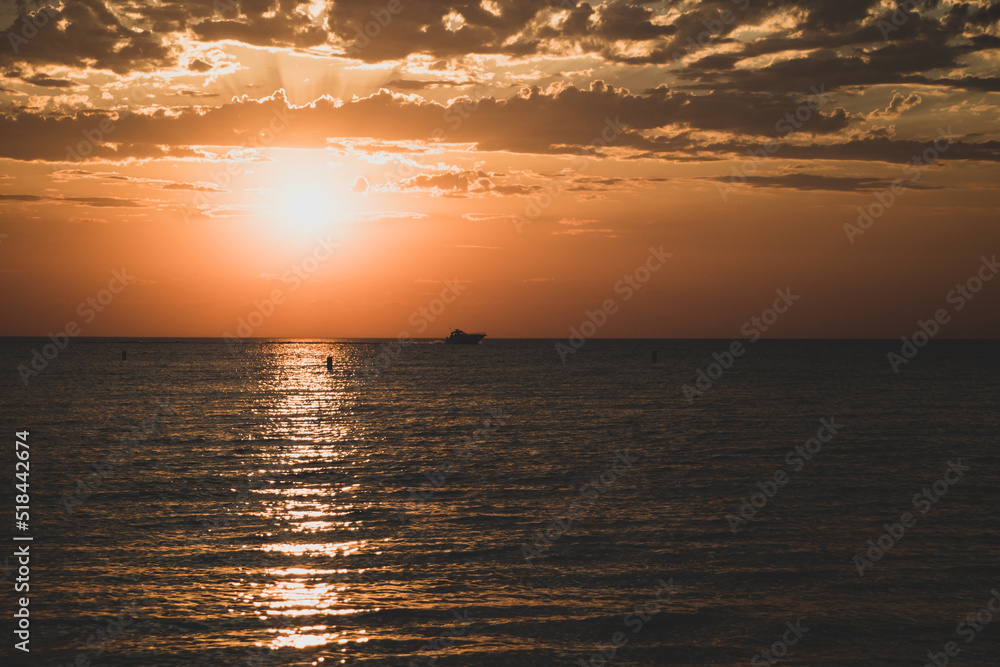 A boat sails through the water at sunset