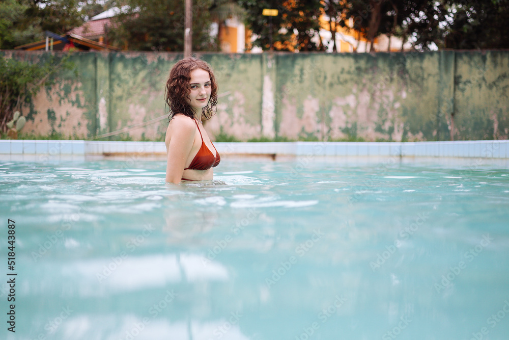 Happy woman playing in the pool during the summer vacations