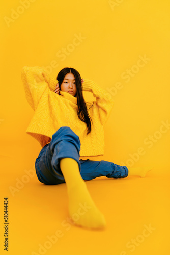 Trendy young Asian woman in yellow sweater in studio photo