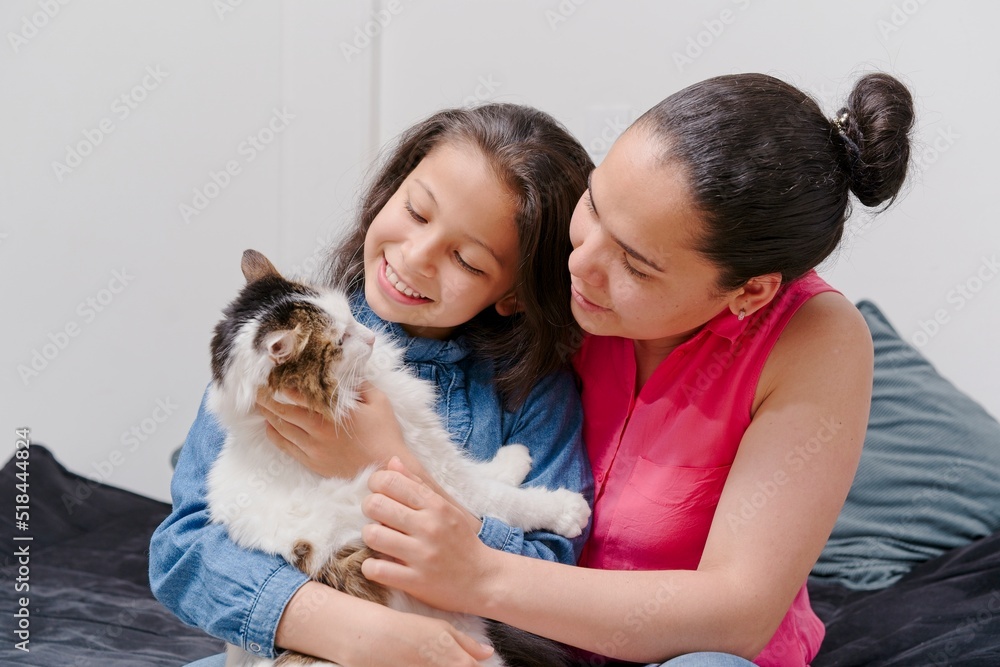 mother and daughter playing with their pet cat mother and daughter playing with their pet cat