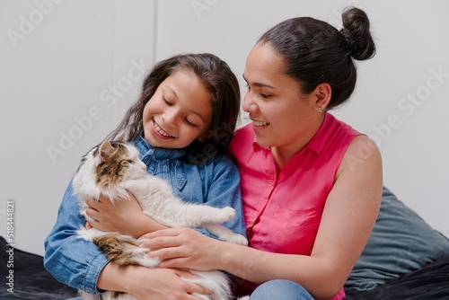 Obraz na płótnie mother and daughter playing with their pet cat w salonie