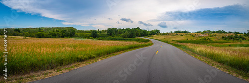 The dramatic landscape with the curving road through golden and green prairie at Big Stone National Wildlife Refuge in Minnesota River, Odessa, Minnesota
