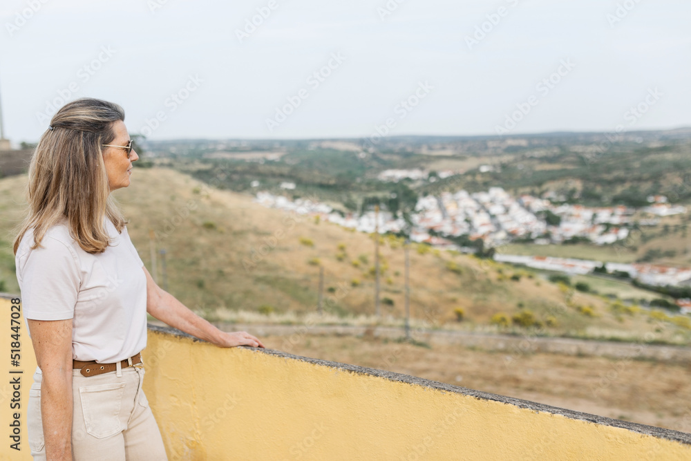 mature woman looking from the top of a town at a landscape mature woman looking from the top of a town at a landscape