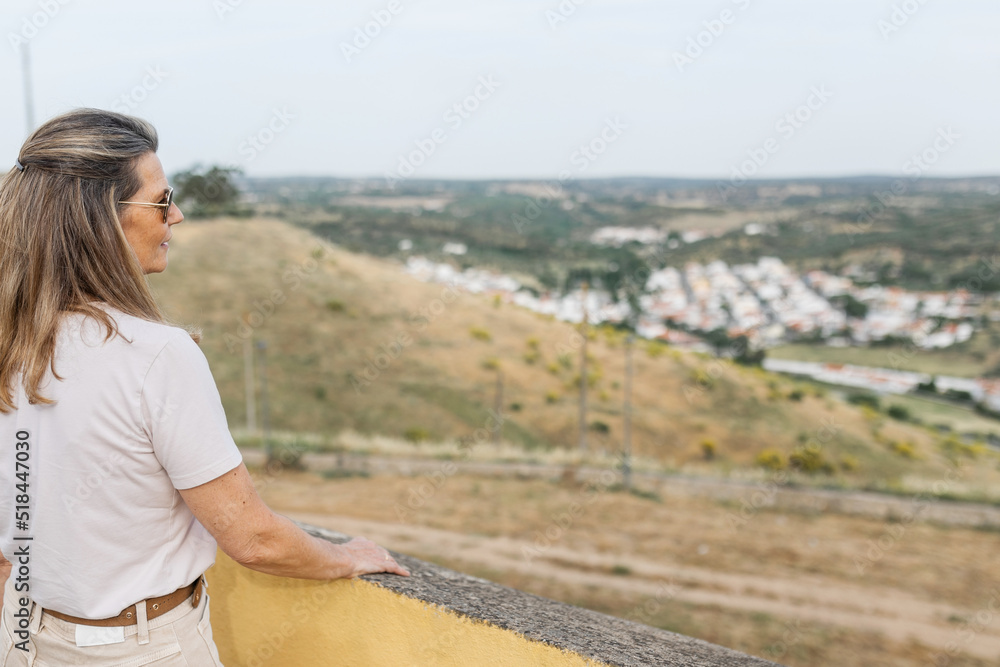 mature woman looking from the top of a town at a landscape mature woman looking from the top of a town at a landscape
