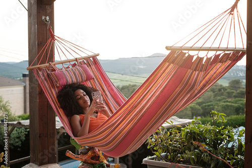 Woman using phone lying in a hammock photo