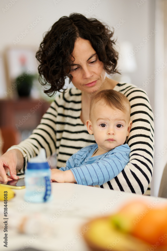 © Guille Faingold/Stocksy - Mother with baby sitting at table. © Guille Faingold/Stocksy - Mother with baby sitting at table.