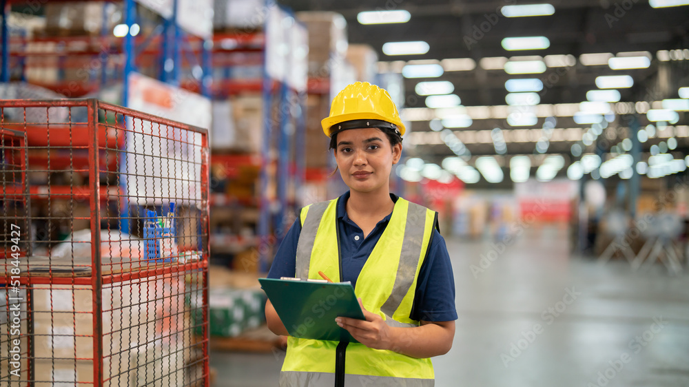 female warehouse worker Work at a distribution center looking at camera Standing at a large warehouse, the new arrival of additional items in the warehouse department. Employees  , organize 