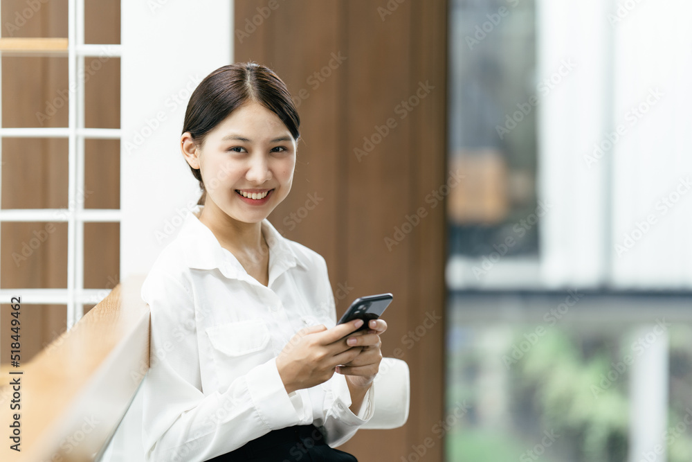 Asian businesswoman in formal suit in office happy and cheerful during using smartphone and working.