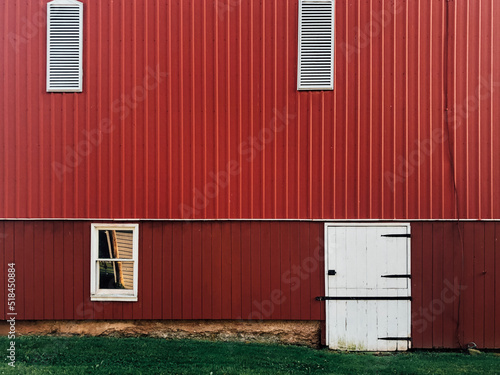 Detail of exterior of side of a red barn with green grass photo