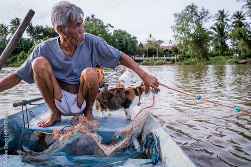 A fisherman checks nets with his cats photo