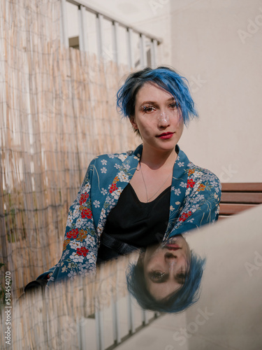 Portrait of acute women with blue short hair reflecting on the glass