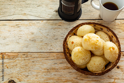 top view of brazilian cheesebread, or 'pão de queijo' with french press coffee maker and mug, over table. copy space photo