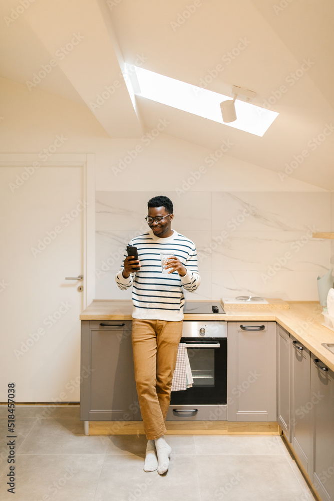 Smiling male looking at cellphone in the kitchen Smiling male looking at cellphone in the kitchen