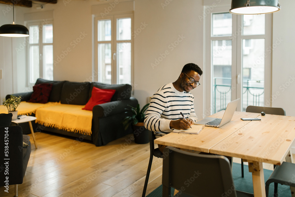 Smiling young man studying with computer at home Smiling young man studying with computer at home