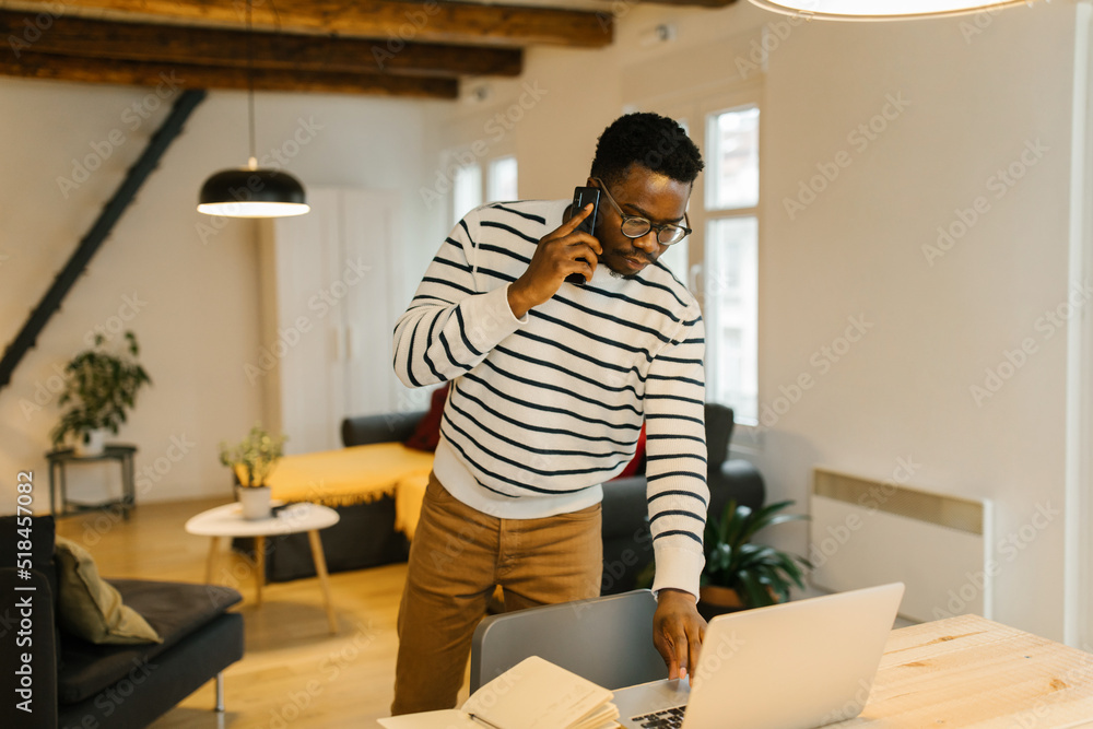 Man talking on the phone and browsing on a laptop Man talking on the phone and browsing on a laptop