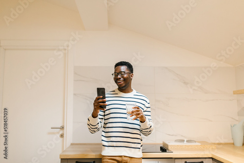 Smiling male looking at cellphone in the kitchen