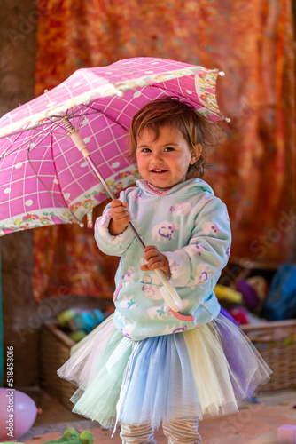 Beautiful little girl having fun smiling and playing with a pink umbrella. 