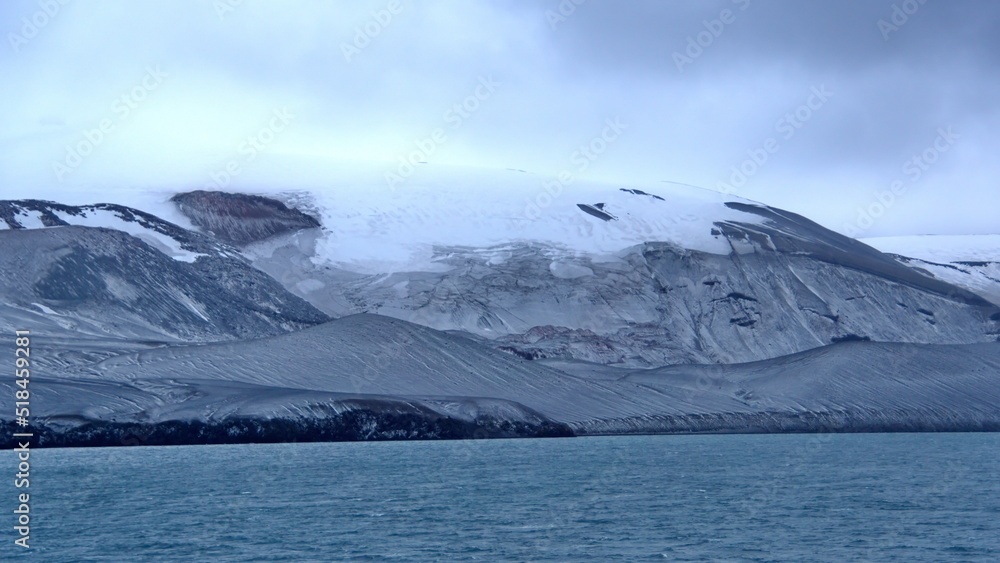 Snow dusted mountains surrounding a crater bay on Deception Island, Antarctica