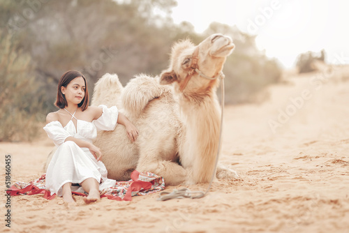 Portrait of asian young woman tourist in white dress and landscape with tourists riding on camels is popular travel destination in Mui Ne desert, Vietnam