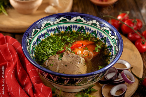 Canvastavla Eastern food - soup shourpa with vegetables and lamb meat on wooden table