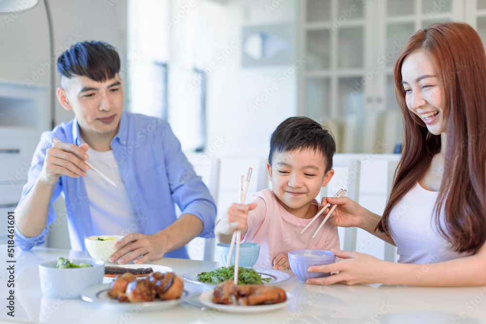  little boy  enjoy eating food with father and mother. Happy Asian  family having dinner at home