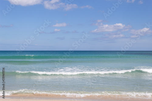 Background of a beach horizon with clouds, the sea with small waves and a bit of sand on the shore