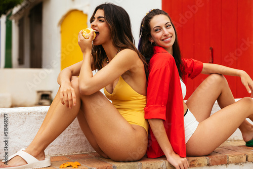 Young women eating fruit and resting on border photo
