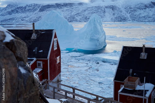 Massive iceberg and outlying settlement houses, Greenland