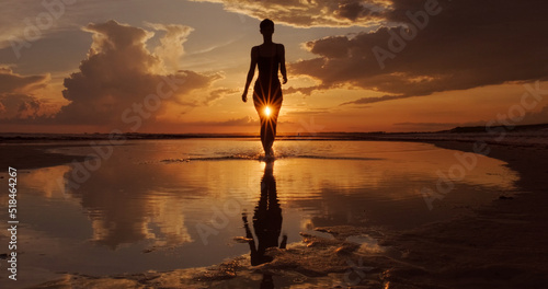 Silhouette of Woman Walking a Sunset Beach  photo