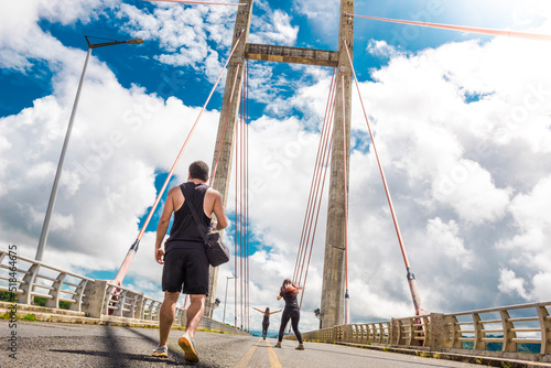 man walking with company on a large bridge with tension cables in the green gulf of Costa Rica in Guanacaste