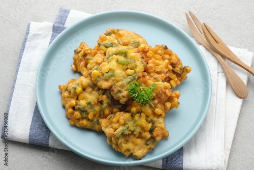 Perkedel Jagung or Bakwan Jagung, corn fritters is Indonesian traditional food. Savoury snack made of corn, egg, flour, spring onion, pepper and salt. Served in plate on grey background.
