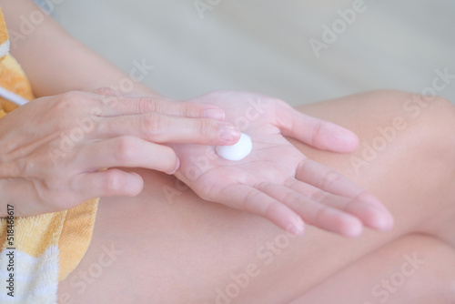 Asia woman sitting on bed and applying cream on her hand.
