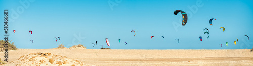 Many kitesurfers on the beach skyline are getting ready to practice Kitesurfing on the Corralejo dunes beach in Fuerteventura, Canary Islands. Spain - Extreme sports concept photo