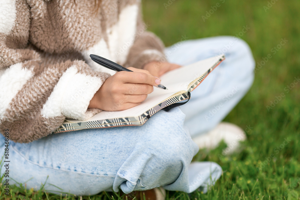 Girl writing notes with pen while sitting in the street.