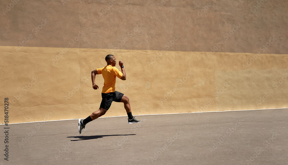 Fit black sprinter running in stadium on sunny day Fit black sprinter running in stadium on sunny day