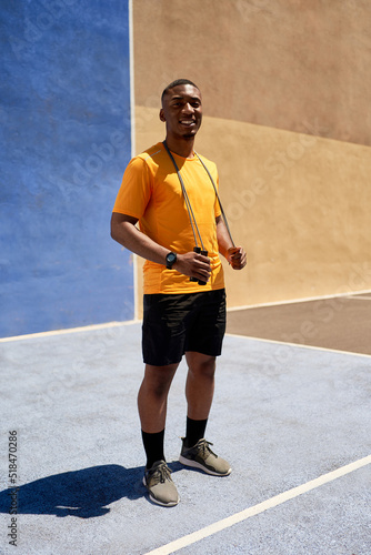 Young black sportsman standing on court in sunlight