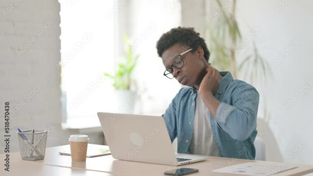 Young African Man having Neck Pain while using Laptop in Office Young African Man having Neck Pain while using Laptop in Office