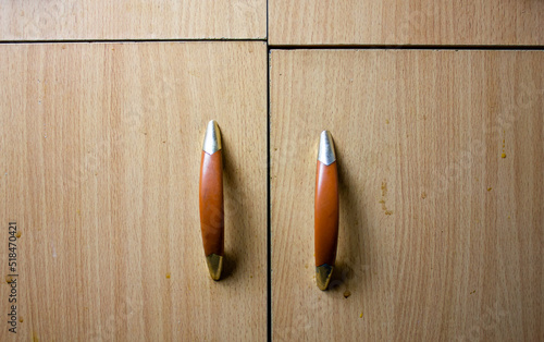 Old uneven cabinet doors with handles. Broken, dilapidated crooked furniture cabinet with handles close-up background.