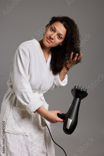 Young lady drying curly hair after taking shower photo