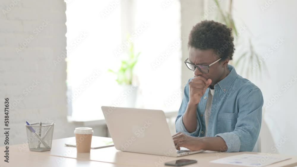 Young African Man Coughing while using Laptop in Office Young African Man Coughing while using Laptop in Office