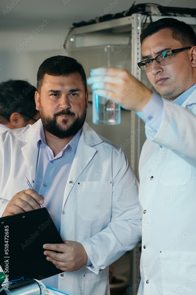 Young chemical technician checking liquid reagent in laboratory Young chemical technician checking liquid reagent in laboratory